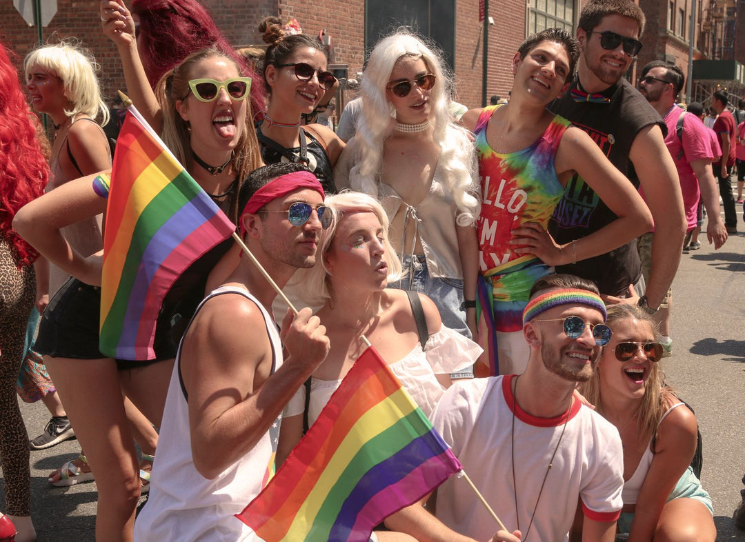 What to wear to Pride — friends in colorful pride outfits with rainbow flags at a parade