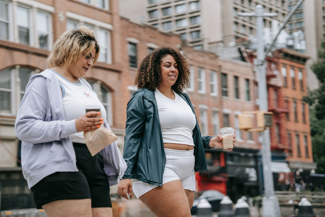 Plus-size pride clothing style guide — two plus-size friends walking together in the city in casual everyday outfits