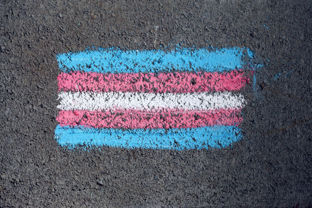 Transgender pride flag with blue, pink and white stripes chalked on pavement — the transgender flag meaning explained